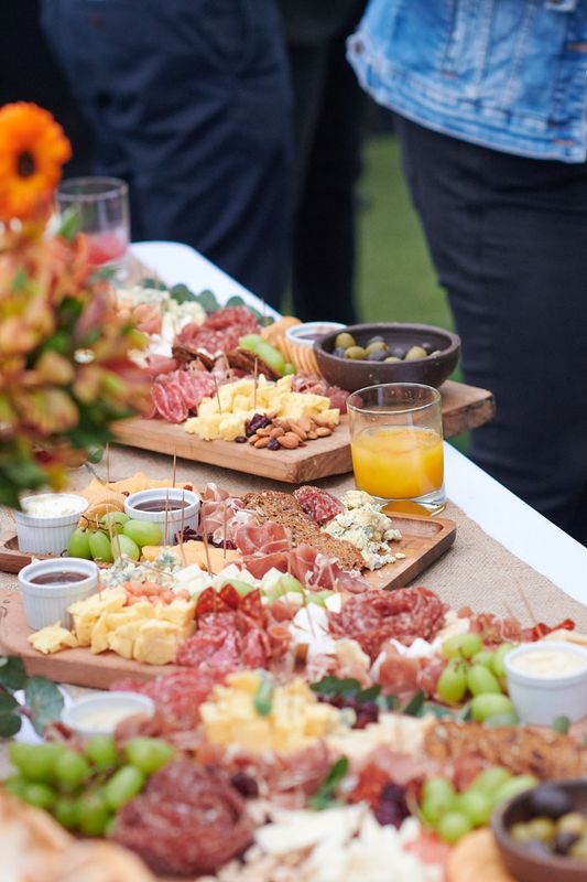 Mesa de charcutería con tablas de quesos, embutidos y frutas